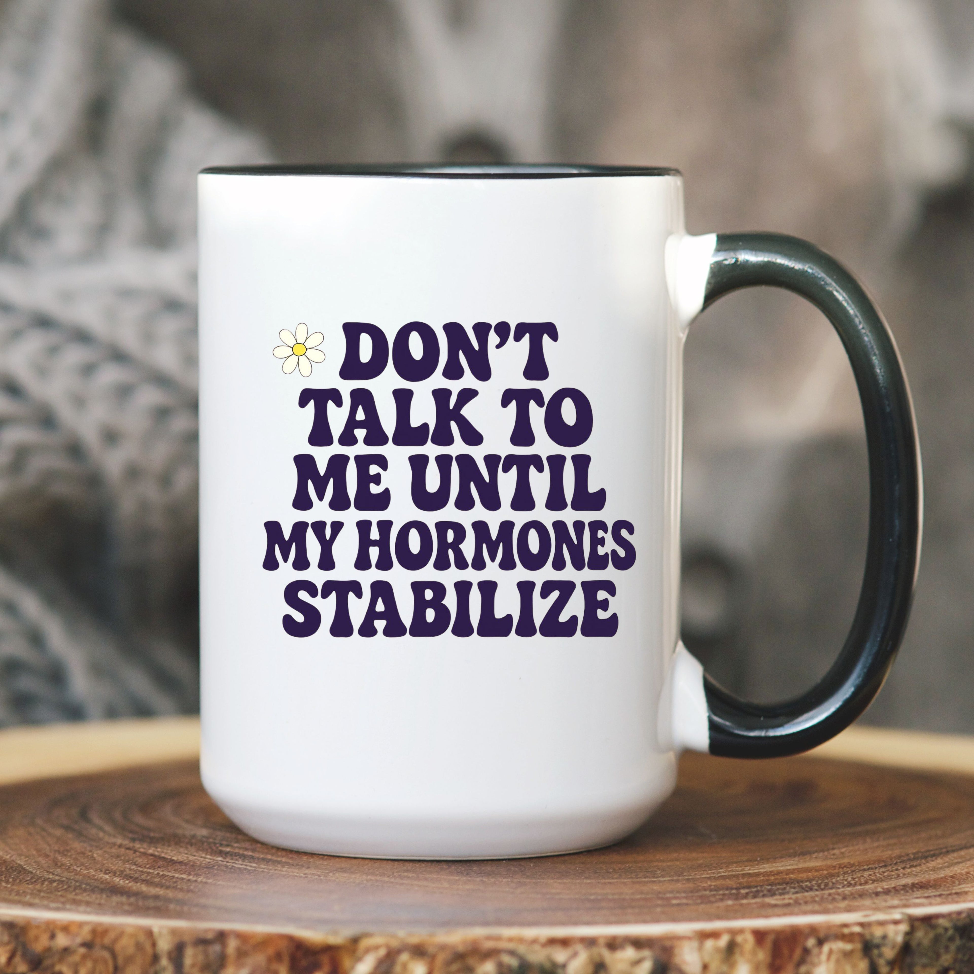 White mug with black handle and text 'DON'T TALK TO ME UNTIL MY HORMONES STABILIZE' on a wooden surface.