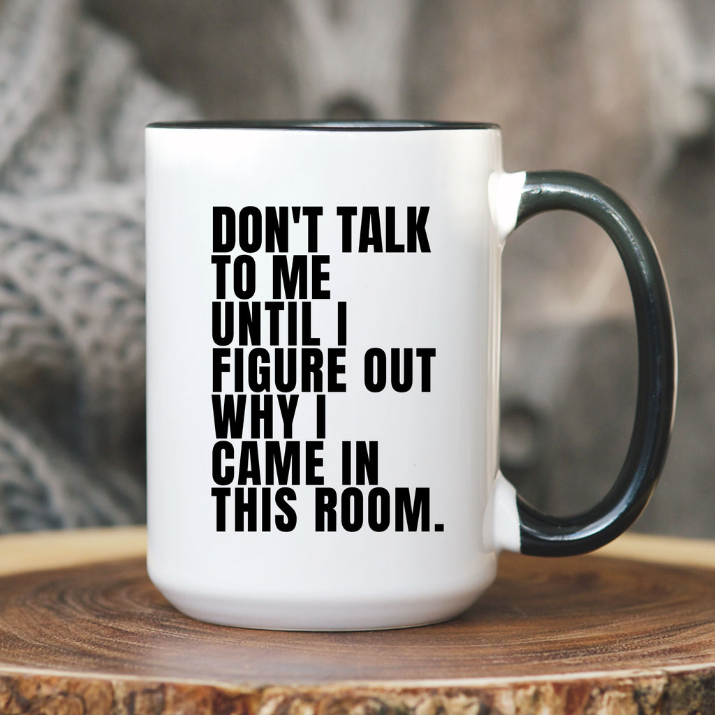 White mug with black handle and 'PERIMENOPAUSAL.' text on a wooden surface.